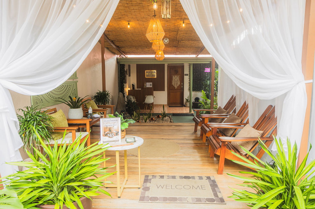 Spa entrance with white drapes, wooden chairs and tropical plants