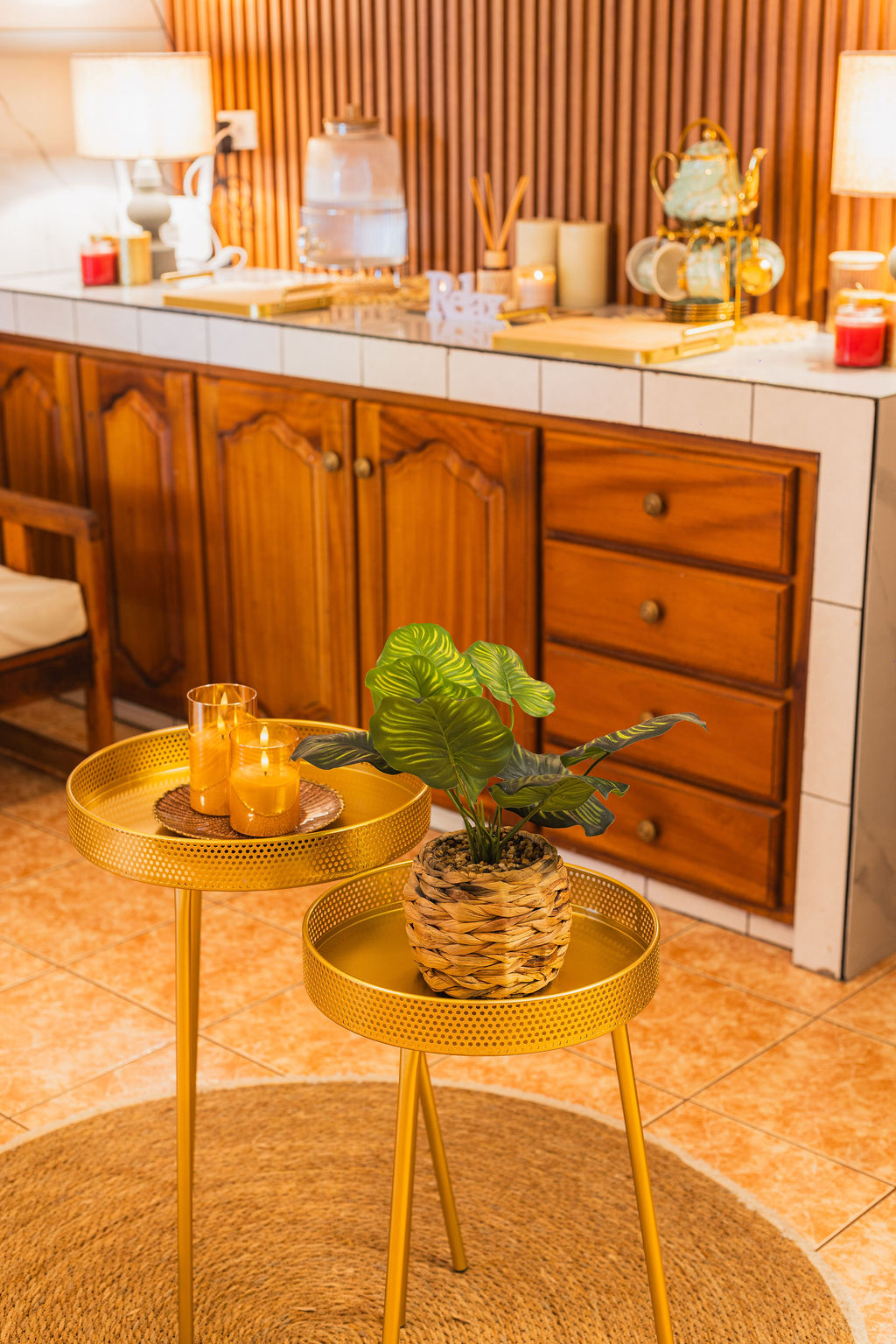 Spa interior with warm wood cabinetry, gold accent tables with candles and a green plant